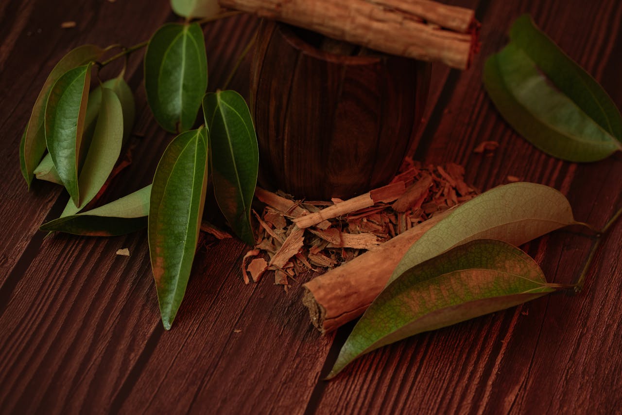 our-experience Cinnamon sticks and leaves on a wooden surface, highlighting their natural beauty.