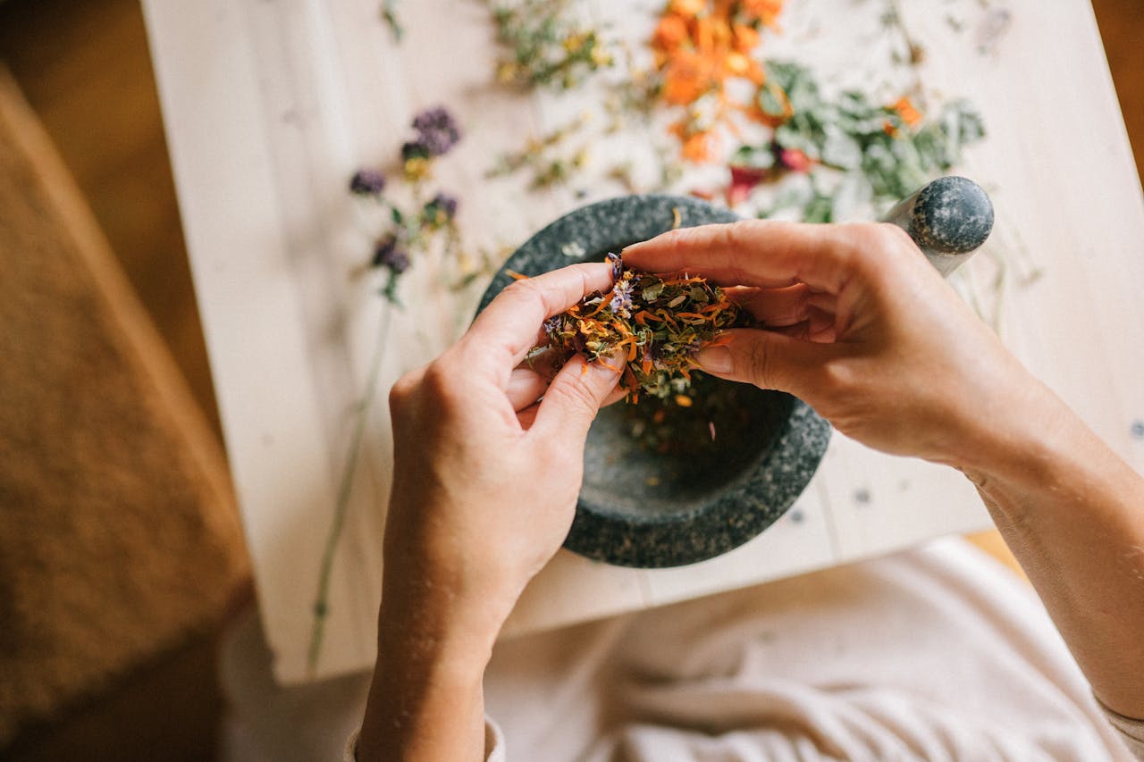 services-img Close-up of hands mixing dried herbs with a mortar and pestle for herbal medicine preparation.